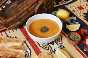 Steaming Bowl of Soup on Table With Bread and Lemons photo