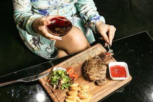 mujer sentado a mesa con plato de comida y vaso de vino foto