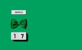 St. Patrick's Day background. Wooden calendar with a leprechaun bow on a green background. Banner. Copy space. photo