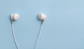 White headphones on a blue background. Music concept. Copy space. photo