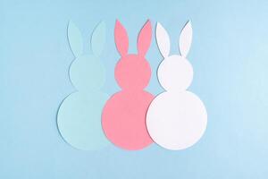 Easter concept. Three paper rabbits on a blue background. Easter background. photo