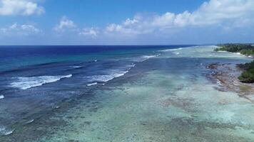 zumbido ver de paraíso islas de el Maldivas con coral arrecifes debajo el olas de azul el indio océano. foto