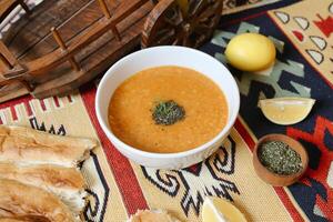 Bowl of Soup With Bread and Lemons on Table photo