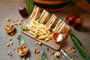 Wooden Cutting Board With Halved Sandwich and French Fries photo