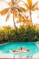 Breakfast in swimming pool, floating breakfast in luxurious tropical resort. Table relaxing on calm pool water, healthy breakfast and fruit plate by resort pool. Tropical couple beach luxury lifestyle photo