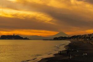 paisaje kamakura yuigahama playa con kamakura ciudad y fujisan montaña. crepúsculo silueta montar fuji detrás enoshima isla a kamakura, kanagawa, Japón. punto de referencia para turista atracción cerca tokio foto