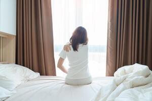 Woman having Shoulder and Neck pain during sitting on bed at home. Muscle painful due to Myofascial pain syndrome and Fibromyalgia, rheumatism, Scapular pain, Cervical Spine. Waking and Health concept photo