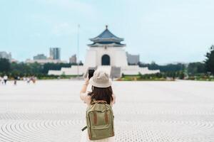 woman traveler visiting in Taiwan, Tourist taking photo and sightseeing in National Chiang Kai shek Memorial or Hall Freedom Square, Taipei City. landmark and popular attractions. Asia Travel concept