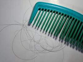 Close-up of comb and hair loss on white background photo