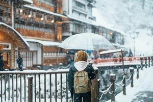 mujer turista visitando ginzan onsen en yamagata, contento viajero Turismo japonés onsen pueblo con nieve en invierno estación. punto de referencia y popular para atracción en Japón. viaje y vacaciones concepto foto