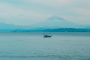 paisaje kamakura yuigahama playa con kamakura ciudad y fujisan montaña. montar fuji detrás enoshima isla a kamakura, kanagawa, Japón. punto de referencia para turista atracción cerca tokio foto