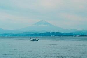 paisaje kamakura yuigahama playa con kamakura ciudad y fujisan montaña. montar fuji detrás enoshima isla a kamakura, kanagawa, Japón. punto de referencia para turista atracción cerca tokio foto