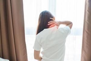 Woman having Neck and Shoulder pain during sitting on bed at home. Muscle painful due to Myofascial pain syndrome and Fibromyalgia, rheumatism, Scapular pain, Cervical Spine. Waking and Health concept photo