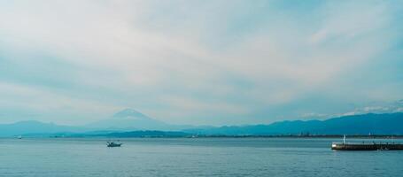 Scenery Kamakura Yuigahama Beach with Kamakura city and Fujisan mountain. Mount Fuji behind Enoshima island at Kamakura, Kanagawa, Japan. Landmark for tourist attraction near tokyo photo