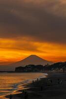 Scenery Kamakura Yuigahama Beach with Kamakura city and Fujisan mountain. Twilight silhouette Mount Fuji behind Enoshima island at Kamakura, Kanagawa, Japan. Landmark for tourist attraction near tokyo photo