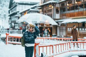 mujer turista visitando ginzan onsen en yamagata, contento viajero Turismo japonés onsen pueblo con nieve en invierno estación. punto de referencia y popular para atracción en Japón. viaje y vacaciones concepto foto