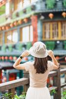 woman traveler visiting in Taiwan, Tourist with hat sightseeing in Jiufen Old Street village with Tea House background. landmark and popular attractions near Taipei city . Travel and Vacation concept photo