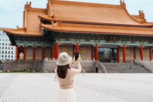woman traveler visiting in Taiwan, Tourist taking photo and sightseeing in National Chiang Kai shek Memorial or Hall Freedom Square, Taipei City. landmark and popular attractions. Asia Travel concept