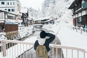 mujer turista visitando ginzan onsen en yamagata, contento viajero Turismo japonés onsen pueblo con nieve en invierno estación. punto de referencia y popular para atracción en Japón. viaje y vacaciones concepto foto