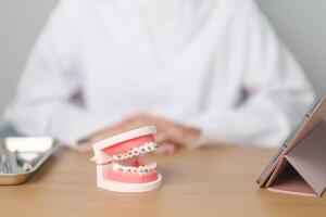 dentista con ortodoncia diente modelo y soporte o abrazadera. limpiar y raspar apagado sarro. mayo ortodoncia salud día, marzo oral salud, dentista día, falso dientes. dolor de muelas y niños dental salud foto