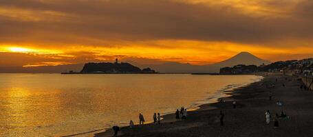 Scenery Kamakura Yuigahama Beach with Kamakura city and Fujisan mountain. Twilight silhouette Mount Fuji behind Enoshima island at Kamakura, Kanagawa, Japan. Landmark for tourist attraction near tokyo photo