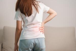 woman having back body ache during sitting on Couch at home. adult female with muscle pain due to Piriformis Syndrome, Low Back Pain and Spinal Compression. Office syndrome and medical concept photo