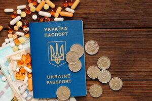 Ukrainian hryvnia money and pills on the table and a Ukrainian passport.. photo