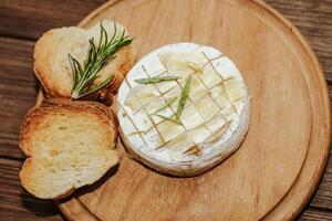 White baguette cut into pieces with olive oil and Camembert cheese on the table. photo
