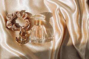 Perfume bottle and silk elastic band on a golden background, beauty routine photo