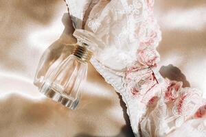 Perfume bottle and silk lingerie on a gold background, beauty routine photo