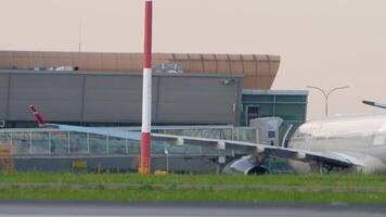 KAZAN, RUSSIA - AUGUST 05, 2022. Passengers are on telescopic gangway from the airplane Nordwind. People walk along the passageway of the airport to the exit to the plane with bags and suitcases video