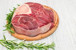 Fresh piece of meat large beef steak on the bone ossobuco with rosemary sprig. photo