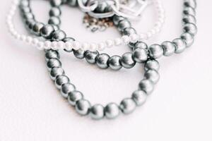 A necklace of gray beads with chain decorations on a white aesthetic background. photo