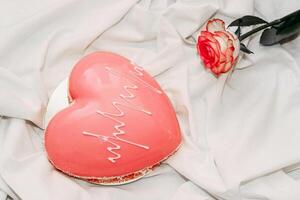 Pink tea rose with heart shaped pink mousse cake. photo