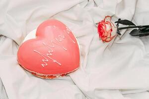 Pink tea rose with heart shaped pink mousse cake. photo