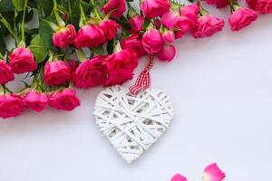 Decorative white heart made of vines, Valentine's Day on the background of a bouquet of roses. photo