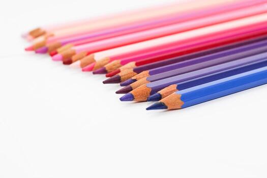 Multi-colored pencils lie on a white table, the violet range of colors photo