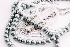 A necklace of gray beads with chain decorations on a white aesthetic background. photo