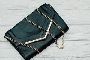 Black clutch bag with gold elements and a gold chain photo