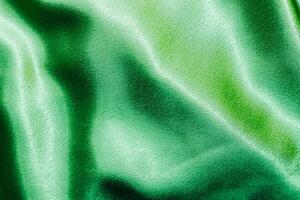 Green shiny texture of silk satin satin with folds. photo