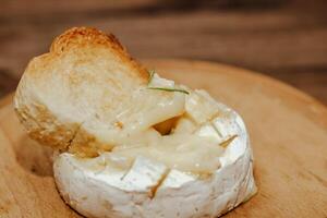 White baguette with olive oil and baked Camembert cheese on the table photo