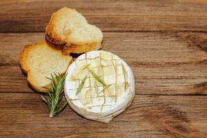 White baguette cut into pieces with olive oil and Camembert cheese on the table. photo