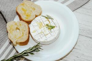 White baguette cut into pieces with olive oil and Camembert cheese on the table. photo