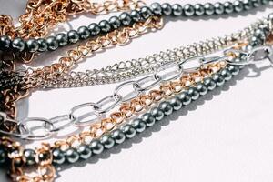 A necklace of gray beads with chain decorations on a white aesthetic background. photo