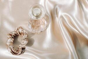 Perfume bottle and silk elastic band on a golden background, beauty routine photo