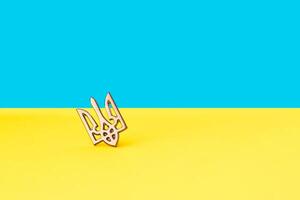 Trident symbol of Ukraine iron badge on the background of the blue-yellow flag photo