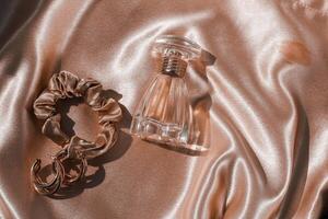 Perfume bottle and silk elastic band on a golden background, beauty routine photo