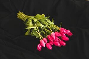 A bouquet of pink flowers sewn on black stylish linen. photo