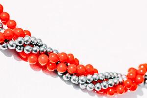 A necklace of red and gray beads on a white aesthetic background. photo