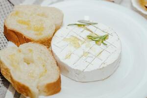 blanco junquillo cortar dentro piezas con aceituna petróleo y queso Camembert queso en el mesa. foto